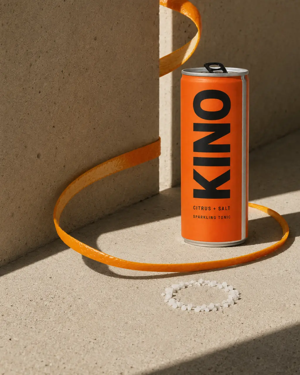 KINO can in a hard-sun concrete setting with a looped kinnow peel shadow
